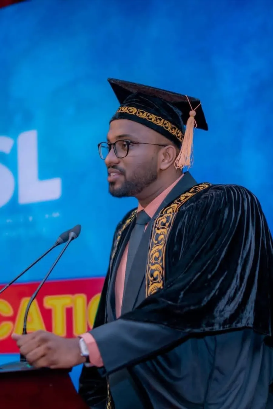 Mayantha Warnakulasooriya speaking at a lectern in graduation cap and gown during a convocation ceremony